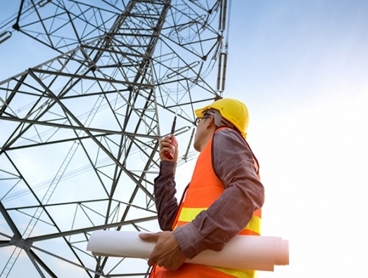 Engineer looking up at a electricity pylon
