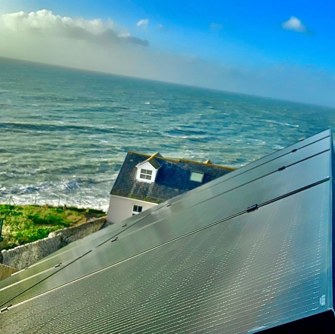 Solar panels on roof of detached home overlooking the sea