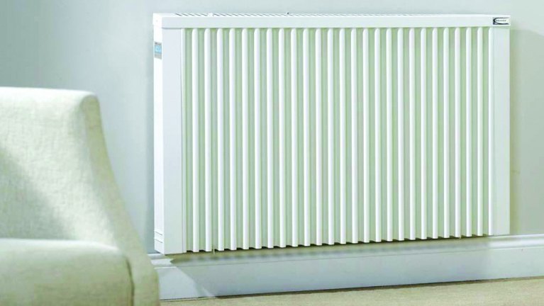 Electric radiator on wall next to a chair